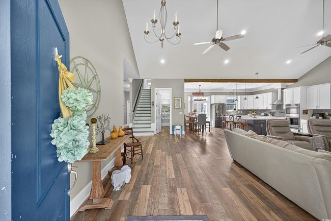 Living room with a ceiling fan, stairway, high vaulted ceiling, dark wood-style floors, and recessed lighting | Image 7