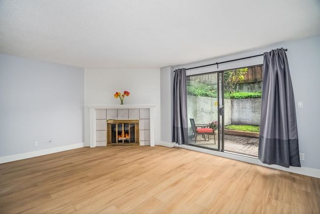 Unfurnished living room with wood finished floors, a tiled fireplace, and baseboards | Image 4