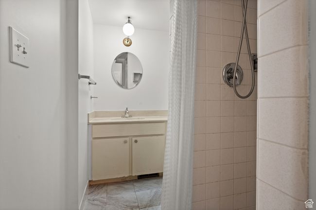 Bathroom with a tile shower, vanity, and marble finish floors | Image 22