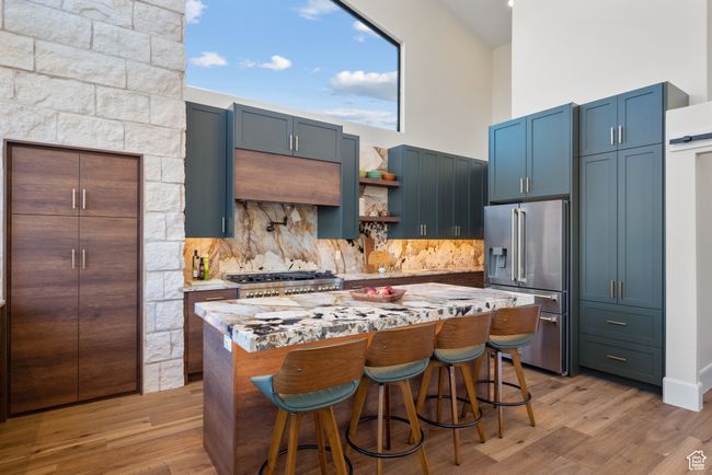 Kitchen with high quality fridge, stove, decorative backsplash, a center island, and light wood-style floors | Image 29