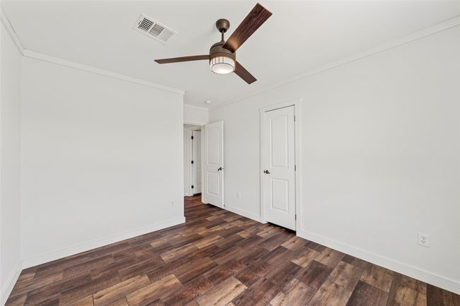 Unfurnished bedroom with crown molding, dark wood finished floors, and a ceiling fan | Image 23