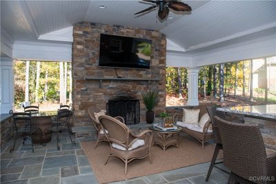 View of patio with ceiling fan and an outdoor living space with a fireplace | Image 2