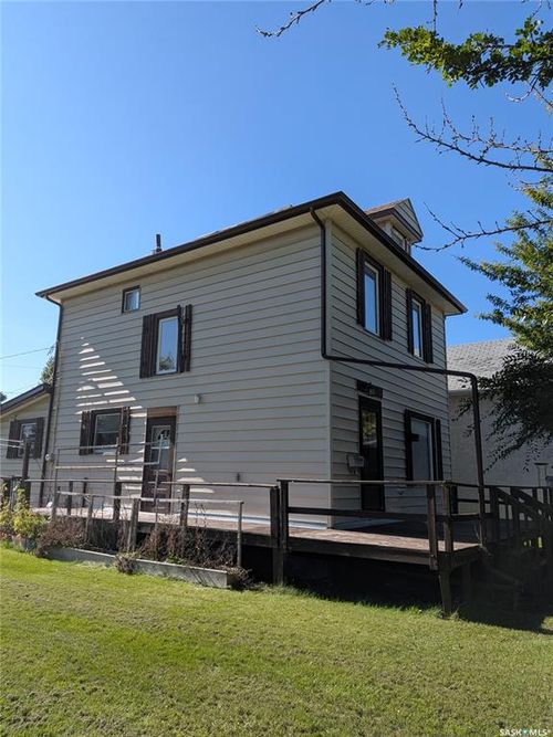 Expansive wooden deck with railing, light-colored horizontal siding, and dark shutters | Card Image