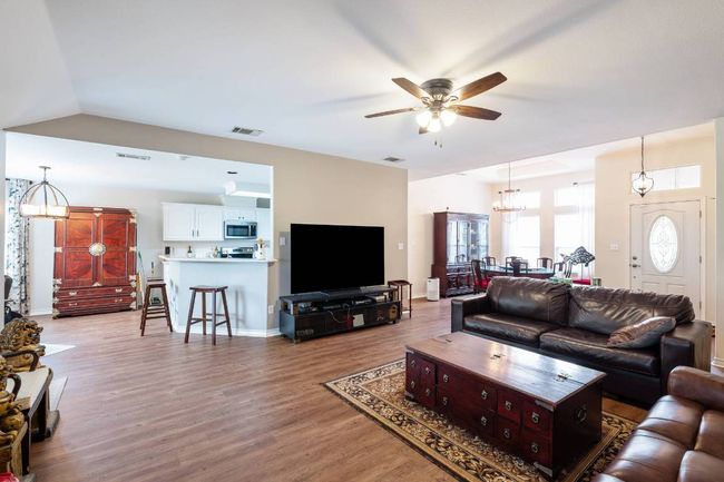 Living room with lofted ceiling, light wood-style flooring, visible vents, and ceiling fan with notable​​‌​​​​‌​​‌‌​‌‌​​​‌‌​​‌‌​‌​​​​​‌ chandelier | Image 18
