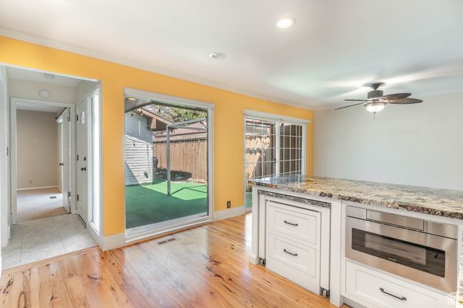 Kitchen with white cabinets, crown molding, light stone countertops, and built in microwave | Image 12