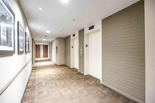 The bright, well-lit hallway with modern design features two elevators with a clean, neutral color palette. | Image 21