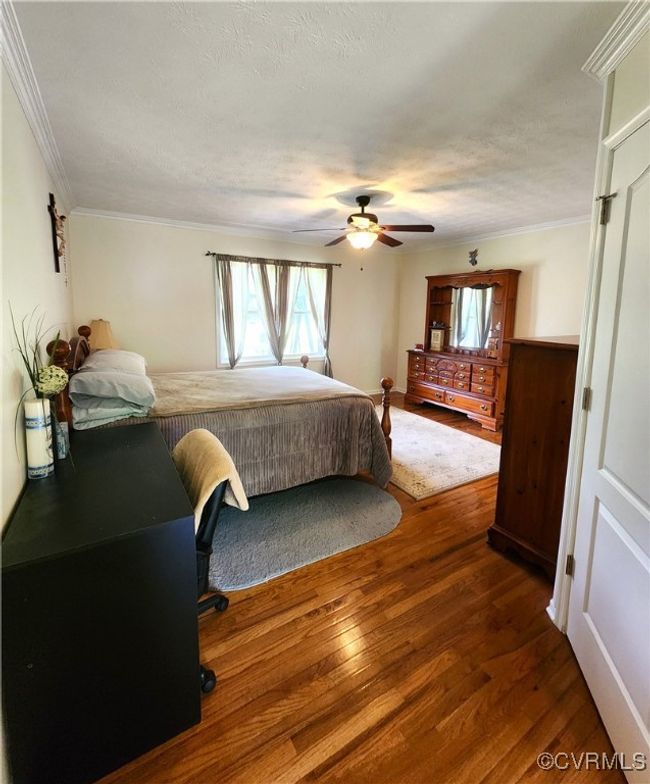 Bedroom with wood finished floors, ornamental molding, a textured ceiling, and a ceiling fan | Image 16