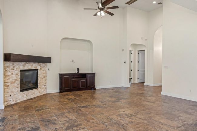 The living area boasts high ceilings with wood beams, a built-in media cabinet, ceiling fan and tons of natural light | Image 24