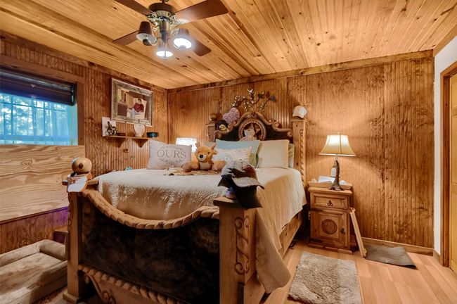 Bedroom featuring a ceiling fan, wood finished floors, wood ceiling, and wood walls | Image 22
