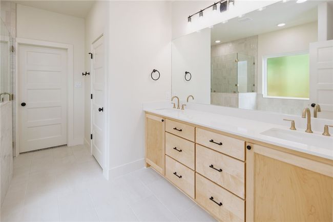 Full bathroom featuring a shower stall, double vanity, tile patterned flooring, and baseboards | Image 17