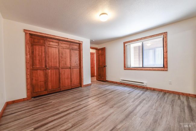 Unfurnished bedroom featuring baseboard heating, light wood-type flooring, and a closet | Image 4