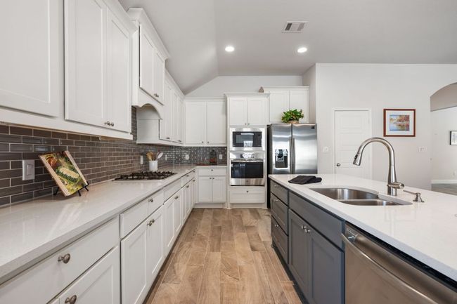 Kitchen featuring white cabinets, visible vents, appliances with stainless steel finishes, and a sink | Image 4