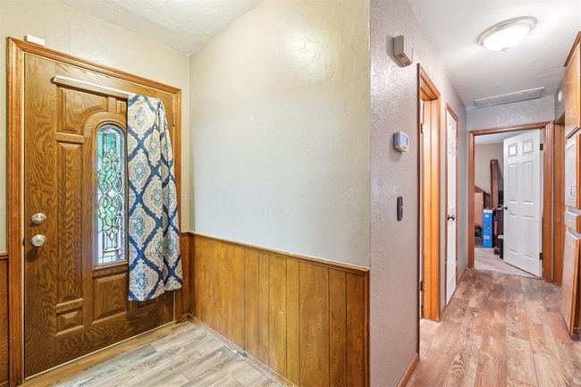 Entryway with light wood-style flooring, a textured wall, wood walls, and a wainscoted wall | Image 7
