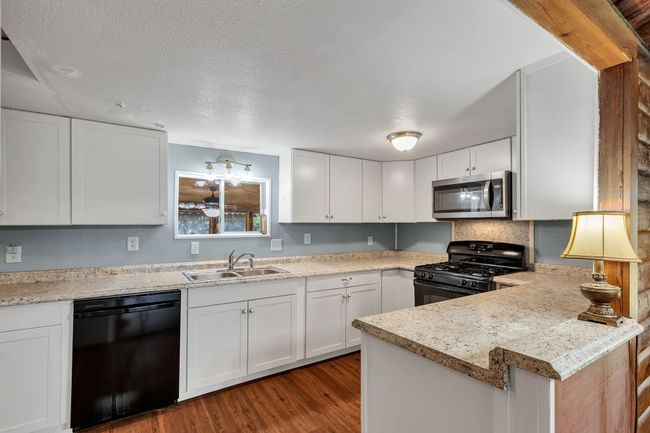 Kitchen featuring white cabinetry, black appliances, light countertops, dark wood finished floors | Image 9