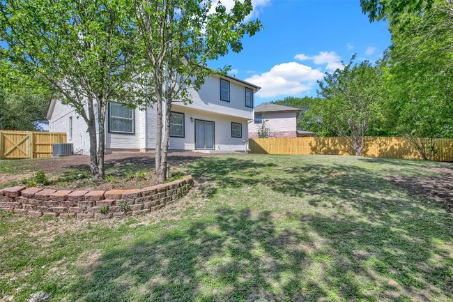 Rear view of property featuring a fenced backyard, a yard, central AC, and a patio | Image 14