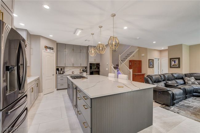 Kitchen featuring recessed lighting, a large island, gray cabinetry, and refrigerator with ice dispenser | Image 24