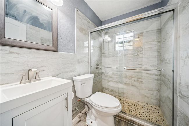 Full bath featuring tile walls, a shower stall, vanity, and wood finished floors | Image 20