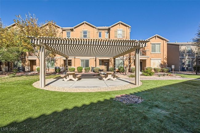 Rear view of property featuring stucco siding, a patio, a lawn, and a pergola | Image 14