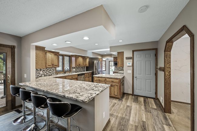 The open concept kitchen with granite countertops, solid wood cabinetry, glass tiled backsplash and stainless steel appliances. The eat-in island is a generous size and allows for seating on both sides. | Image 16