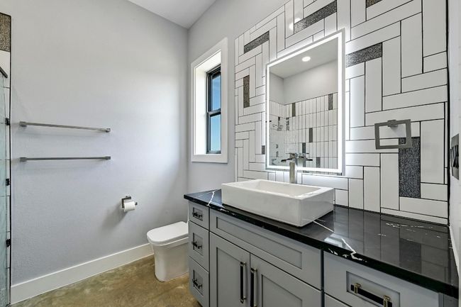 The guest ensuite bathroom is also adorned with designer finishes, a lit mirror, and unique modern backsplash. | Image 25
