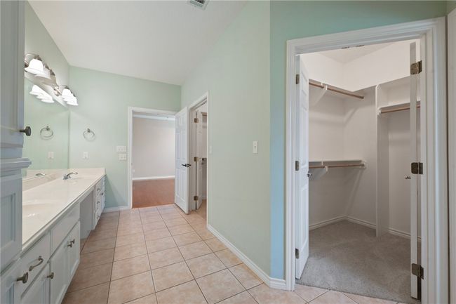 Full bathroom featuring double vanity, a walk in closet, tile patterned floors, and baseboards | Image 21
