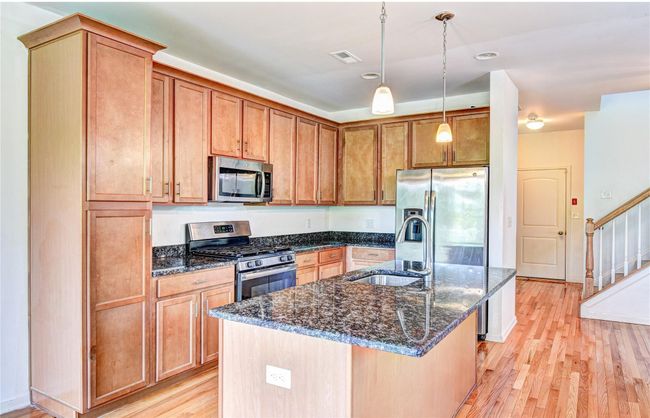 Kitchen with appliances with stainless steel finishes, a sink, hardwood flooring, granite counters, and a kitchen island with sink | Image 10