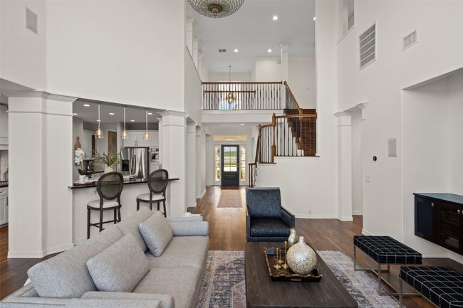 Living area with stairs, wood finished floors, baseboards, visible vents, and ornate columns | Image 9