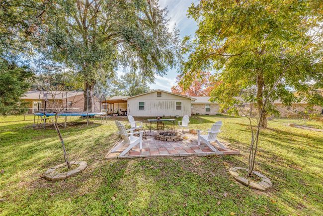 View of green lawn featuring a trampoline, an outdoor fire pit, and a patio area | Image 24