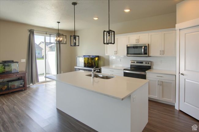 Kitchen featuring a sink, appliances with stainless steel finishes, dark wood-style floors, white cabinetry, and a center island with sink | Image 10