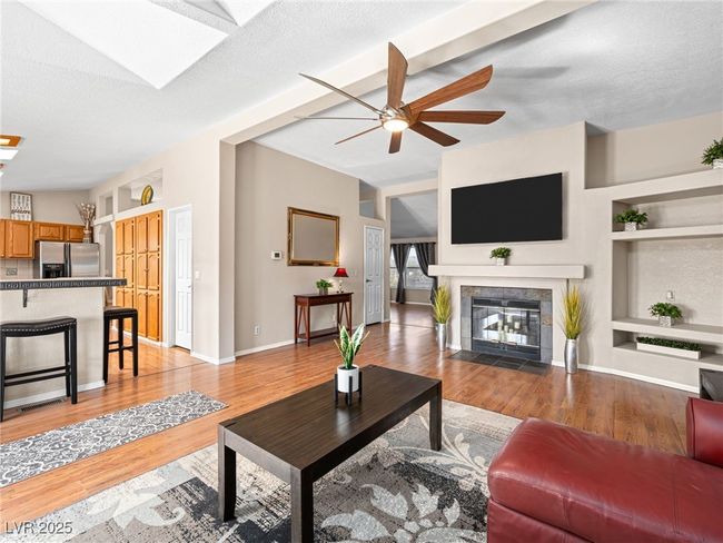 Living area featuring a fireplace, built in features, a ceiling fan, and light wood-style floors | Image 14