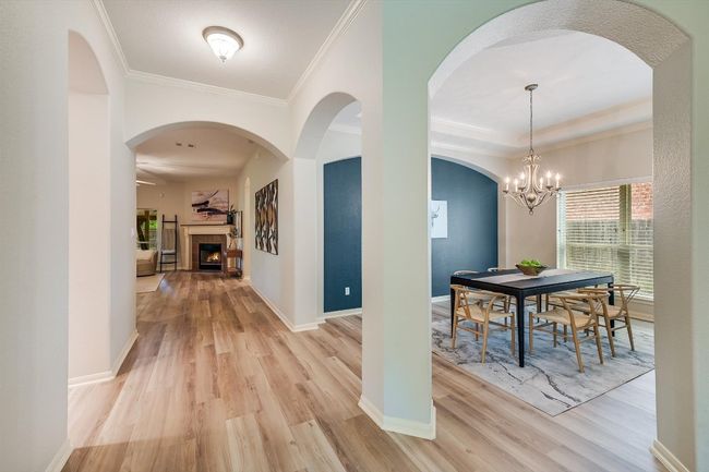 Foyer with light wood finished floors, ornamental molding, a lit fireplace, and a chandelier | Image 12