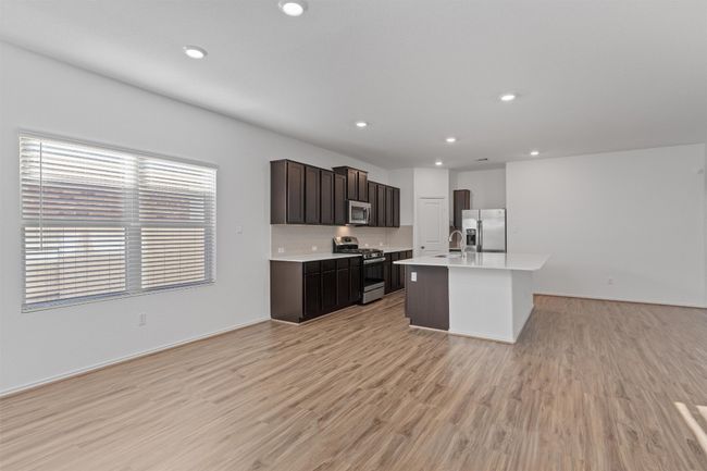 Kitchen with an island with sink, stainless steel appliances, light countertops, light wood-type flooring, and a sink | Image 4