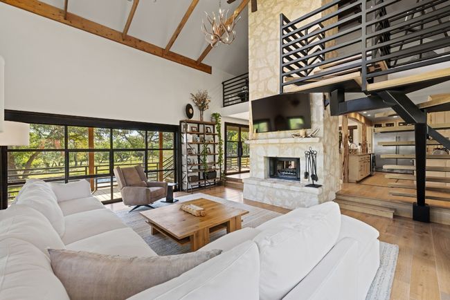 Living room with high vaulted ceiling, hardwood / wood-style flooring, a large fireplace, beam ceiling, and a chandelier | Image 20