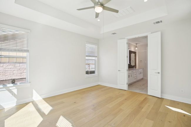 Unfurnished bedroom featuring a tray ceiling, light wood-type flooring, and visible vents | Image 11