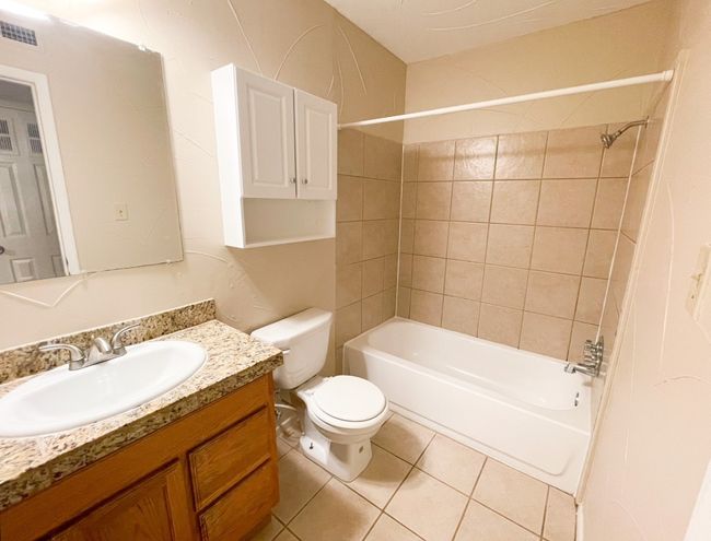 Full bath with vanity, tub / shower combination, tile patterned floors, and toilet | Image 8