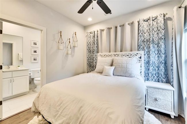Bedroom with ensuite bathroom, wood finished floors, and ceiling fan | Image 13