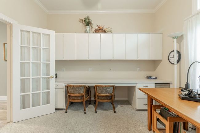 Office space featuring light carpet, ornamental molding, and built in desk | Image 17