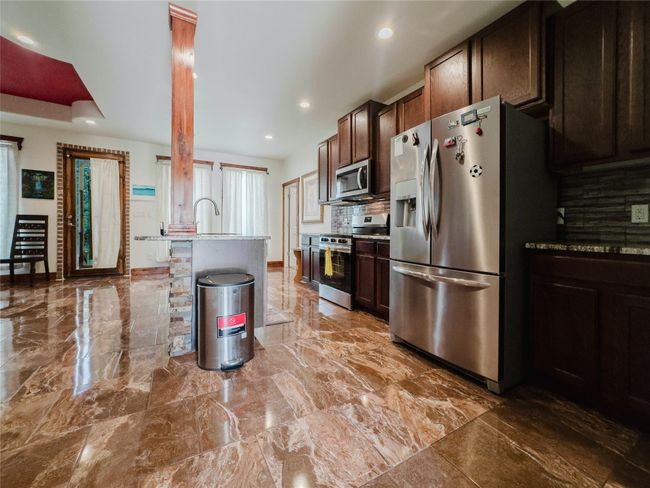 Kitchen with appliances with stainless steel finishes, recessed lighting, marble finish flooring, backsplash, and dark brown cabinetry | Image 9