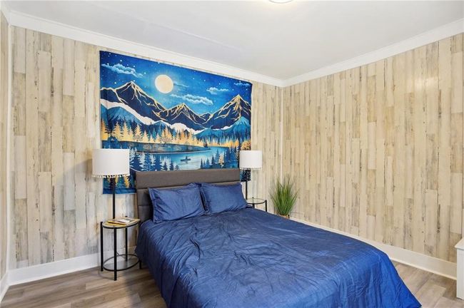 Bedroom featuring wooden walls, wood finished floors, and baseboards | Image 12