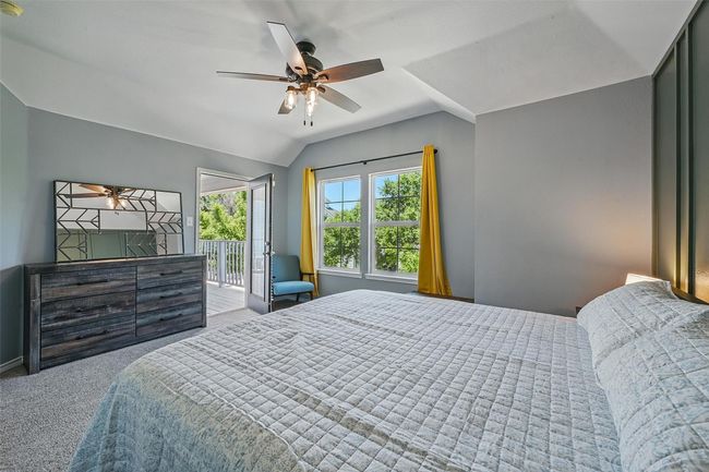 Bedroom featuring access to exterior, carpet flooring, vaulted ceiling, a ceiling fan, and baseboards | Image 34
