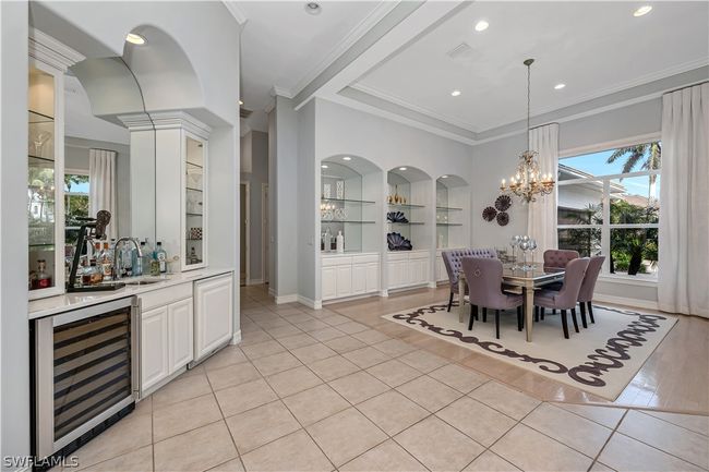 Dining room showcases a wet bar, Uline refrigerator and wine cooler. Lighted glass enclosed cabinetry with glass shelving supplement the glass shelving and storage nooks in the dining room | Image 8