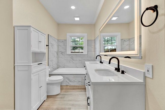 Bathroom featuring double vanity, wood finished floors, a tub to relax in, and a sink | Image 21