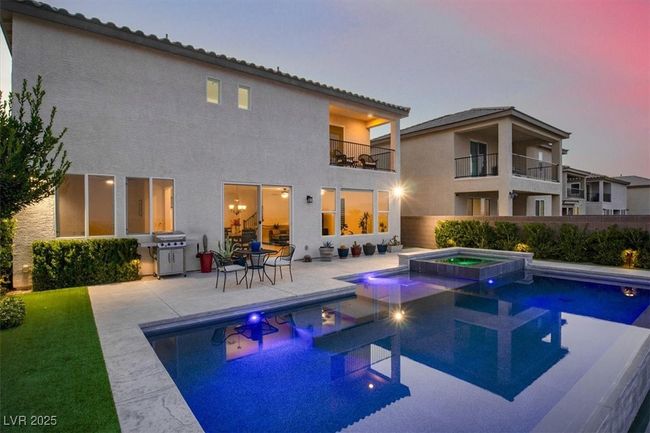 Back of property at dusk with a balcony, a patio, a pool with connected hot tub, and stucco siding | Image 52
