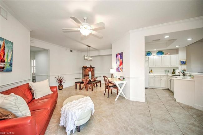 Living area with a ceiling fan, light tile patterned flooring, crown molding, and visible vents | Image 10