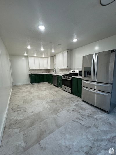 Kitchen featuring green cabinets, sink, white cabinets, appliances with stainless steel finishes, and a textured ceiling | Image 2