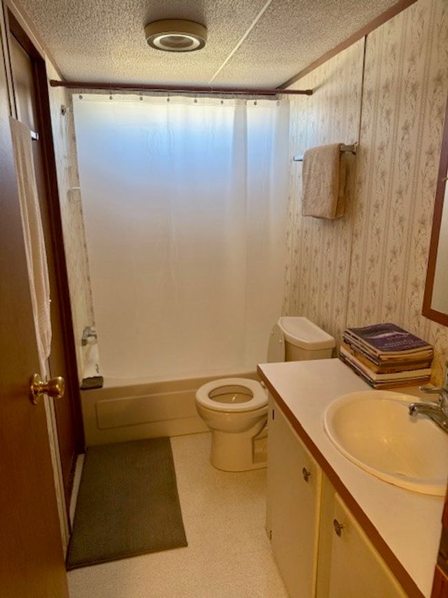 Bathroom featuring a textured ceiling, toilet, shower / bath combination with curtain, and vanity | Image 21