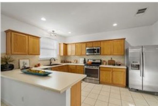 Kitchen featuring brown cabinetry, stainless steel appliances, light countertops, and a peninsula | Image 11