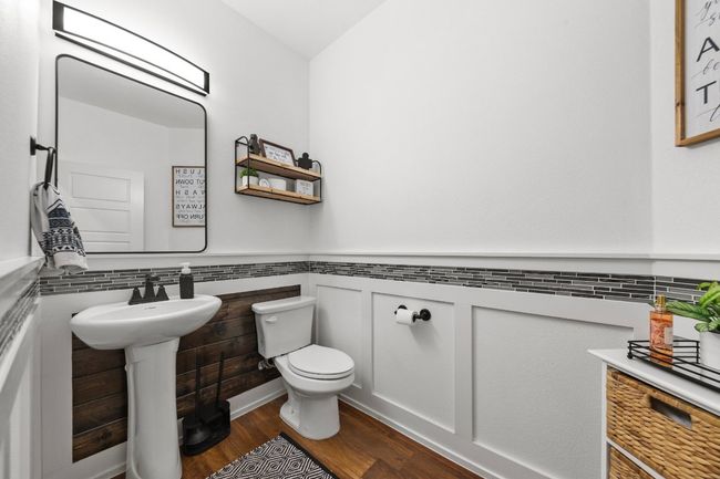 Half bath with wainscoting, a sink, toilet, and wood finished floors | Image 5