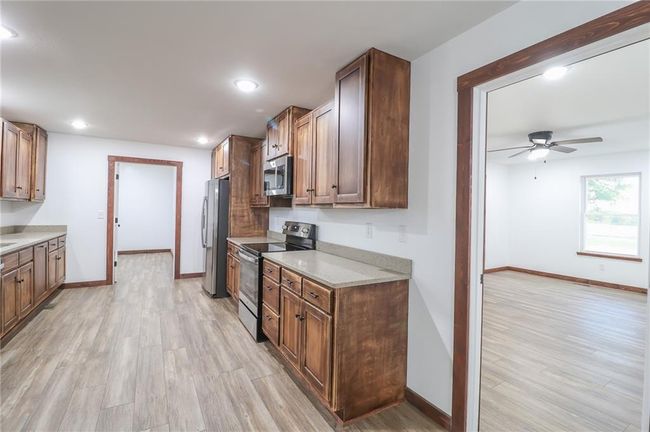 Kitchen with ceiling fan, light stone countertops, appliances with stainless steel finishes, and light hardwood / wood-style flooring | Image 17