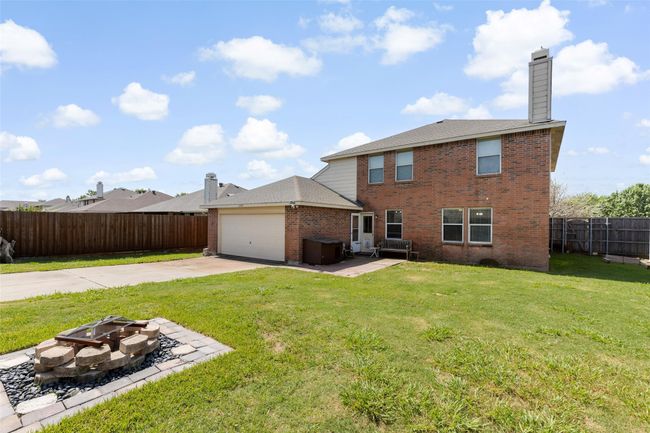 Rear view of property with brick siding, a fire pit, driveway, a chimney, and a fenced backyard | Image 31